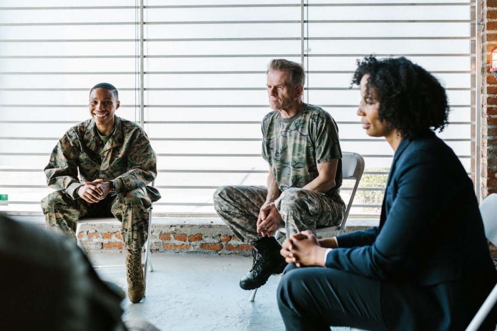 Therapist sitting in circle with two men in military uniform