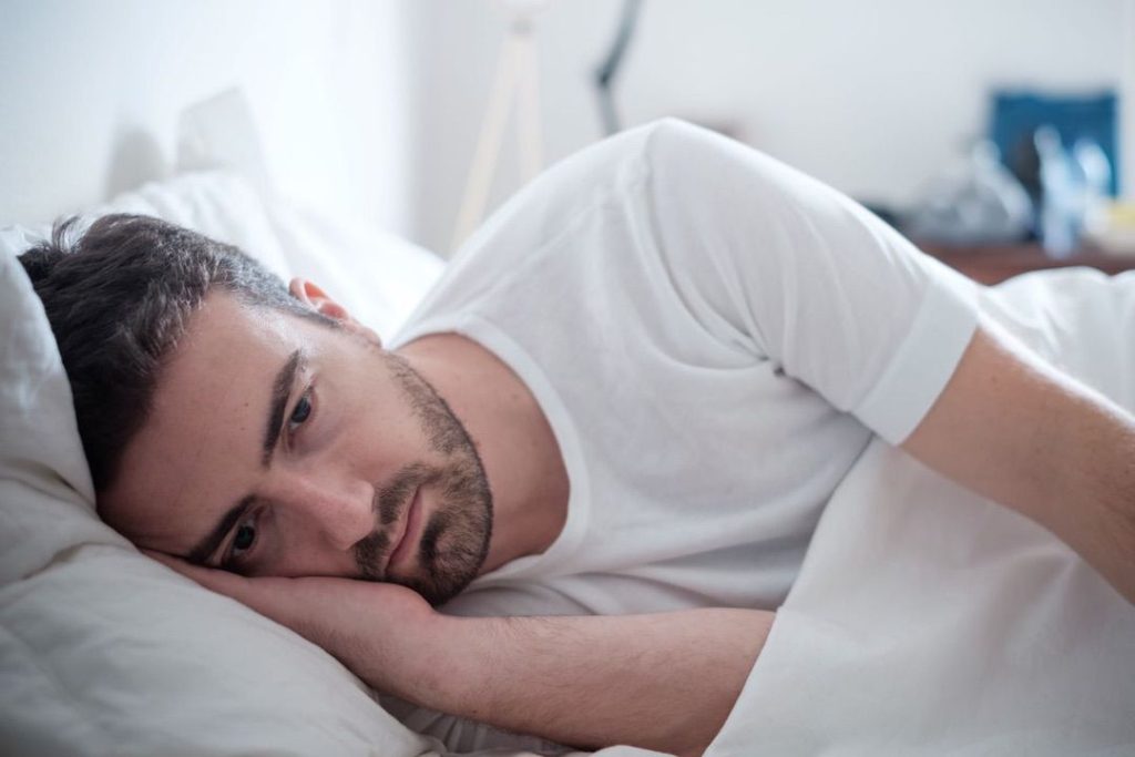 Man laying in bed with eyes open
