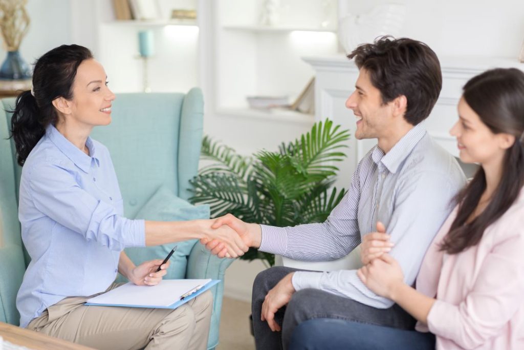 Therapist smiling and shaking hands with couple sitting
