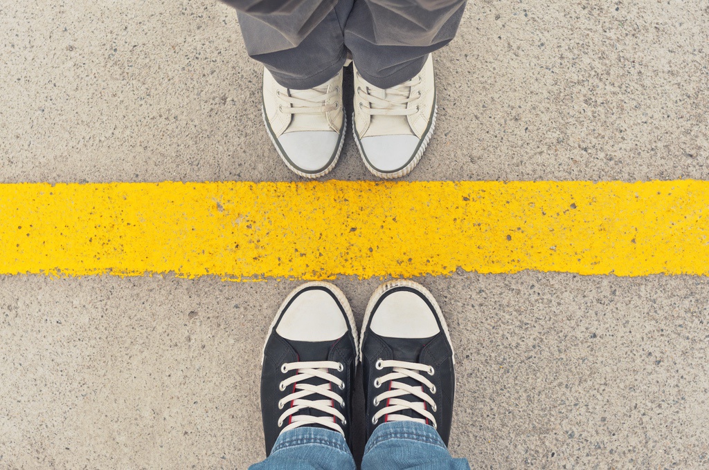 Two pairs of feet separated by painted yellow line to symbolize setting boundaries