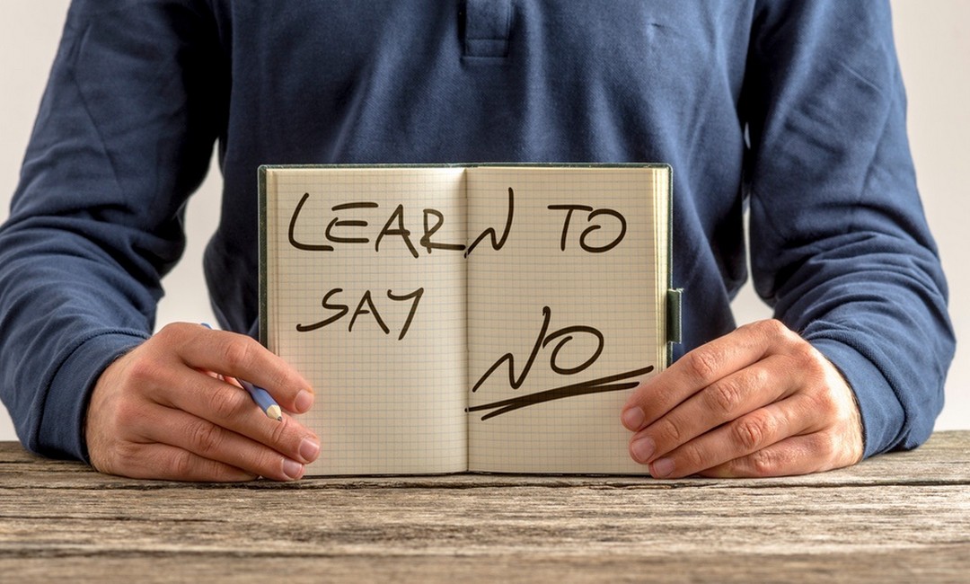 Man holding notebook with Learn to Say No written inside