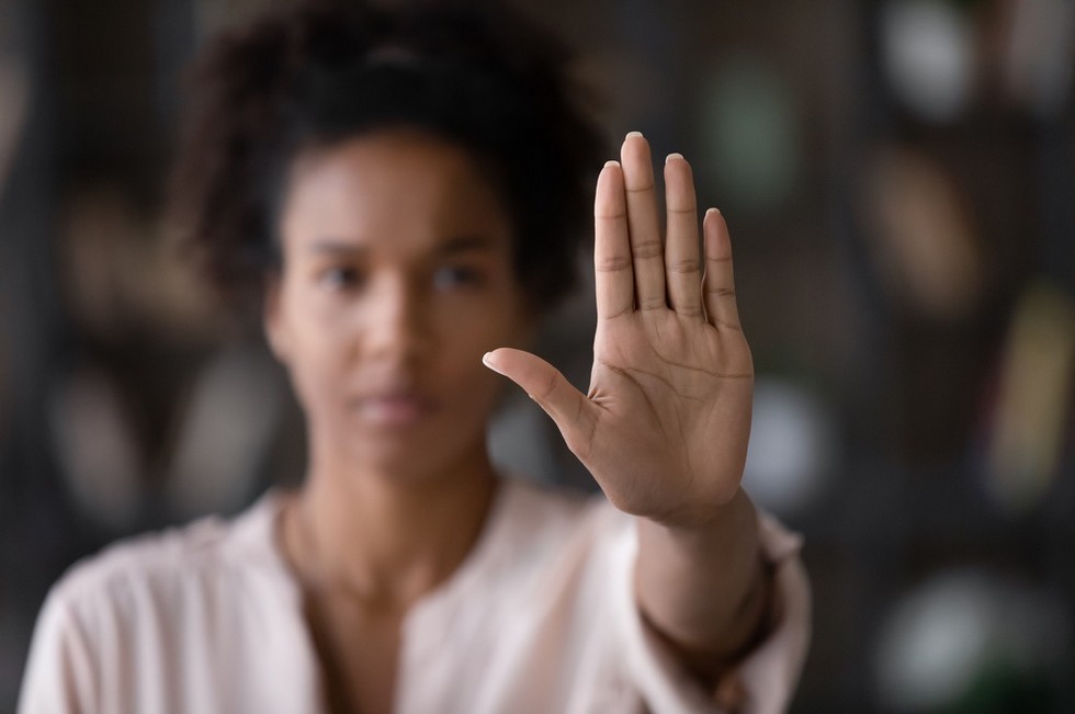 Woman raising hand to symbolize saying no and setting boundaries