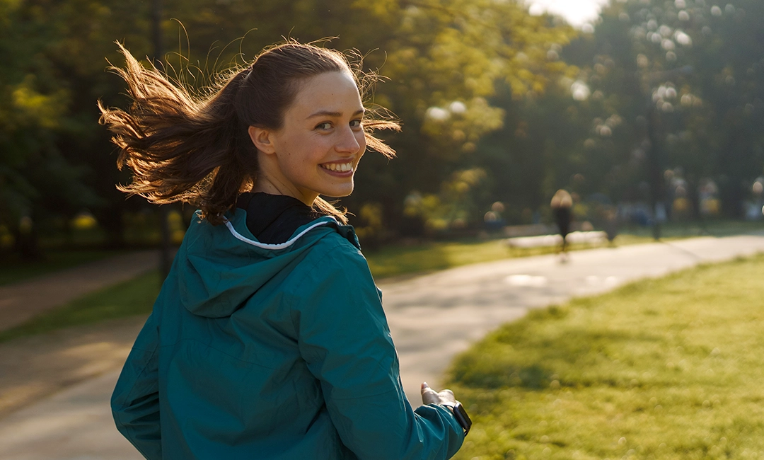 Woman jogging on path with huge smile on her face
