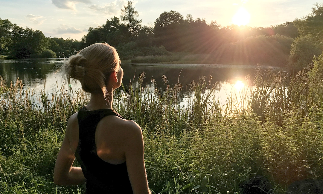 Woman overlooking small pond during sunset