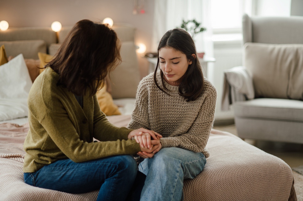 Mother asking young teenage daughter how she is feeling during puberty to help assess mental health