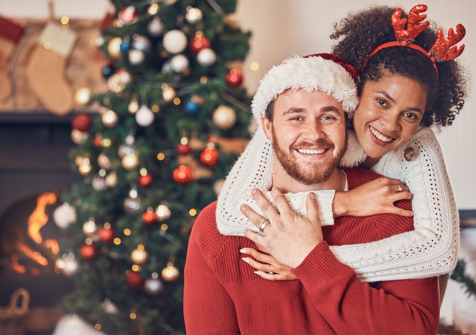 Smiling couple in front of Christmas tree during holiday season after seeking mental health support