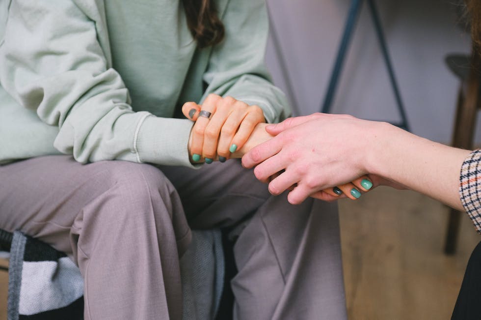 Women holding hands in counseling session discussing mental health