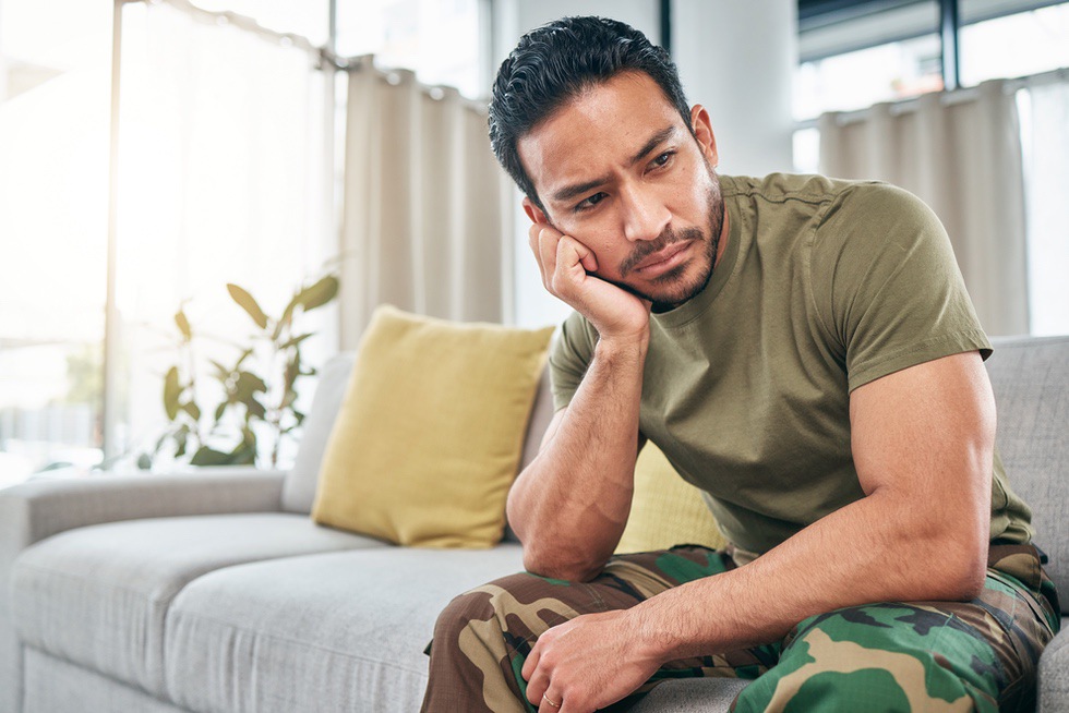 Upset man sitting on couch while experiencing mood swings as symptom of sex addiction withdrawal